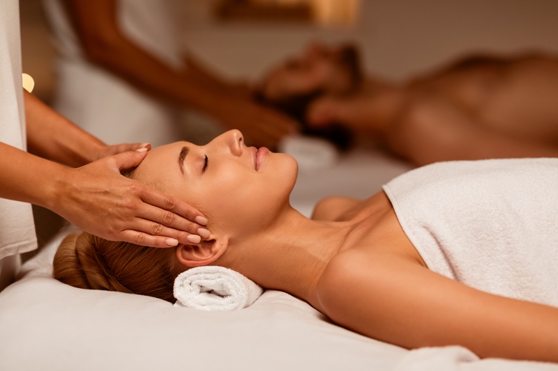 Couple Receiving Acupressure Head Massage Relaxing With Eyes Closed In Luxury Spa Center. Beauty And Relaxation Therapy, Couples Wellness And Rejuvenation Concept. Low Light, Selective Focus